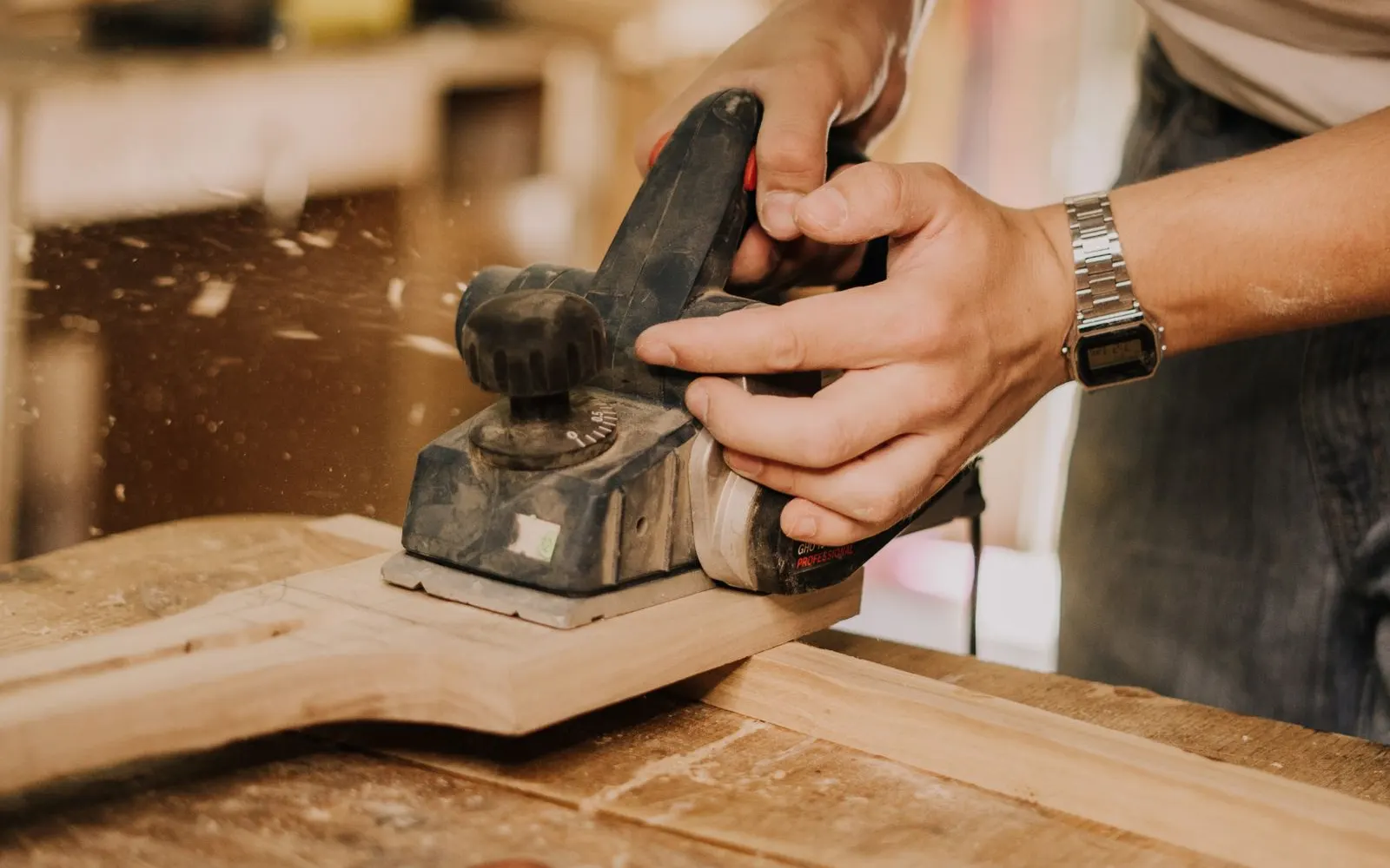 Handwerker bearbeitet ein Holzbrett mit einem Hobel in der Werkstatt